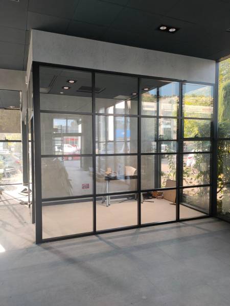 Installation de cloison aluminium type verrière industrielle dans un showroom